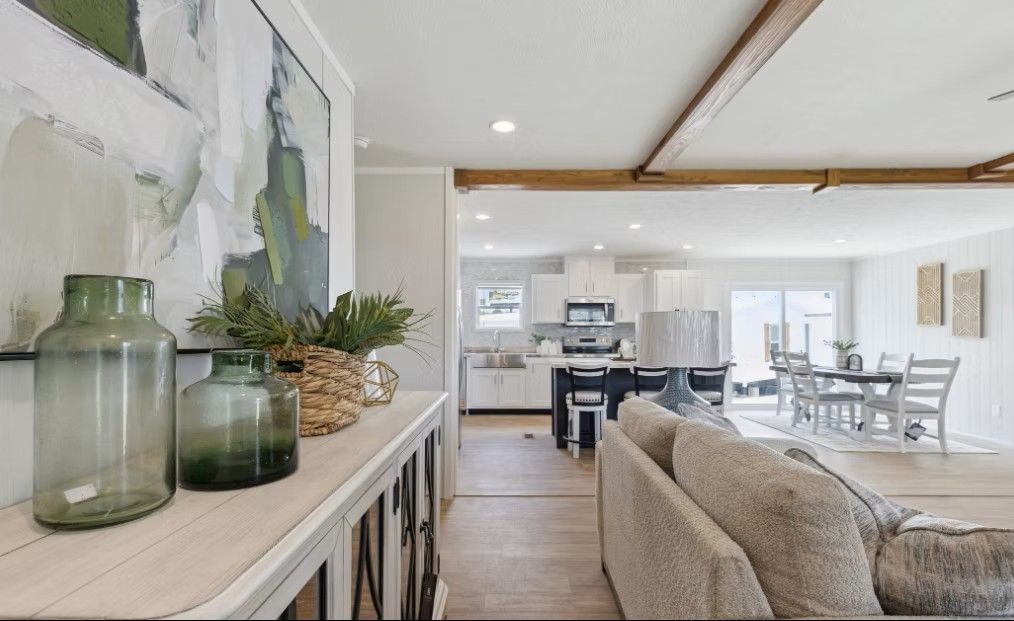 Living room interior with open layout to kitchen and dining area, featuring neutral tones and decor.