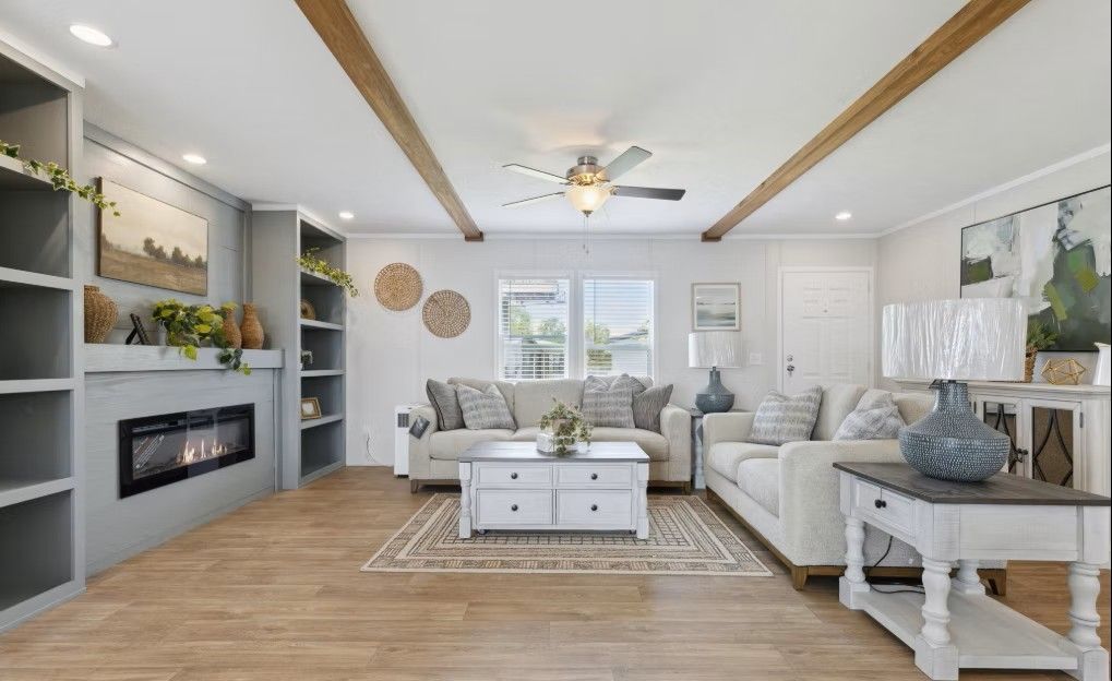 Spacious living room with fireplace, sofas, and coffee table. Neutral color scheme, wood beams, and built-in shelving.