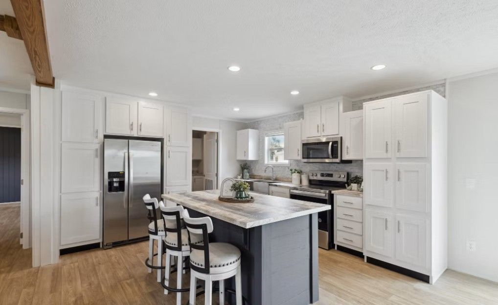 Modern white kitchen with island, stainless steel appliances, and wooden floors.