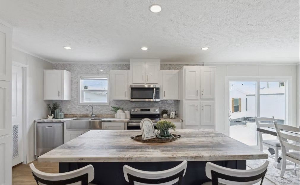 White kitchen with island, stainless steel appliances, and sliding door to backyard.
