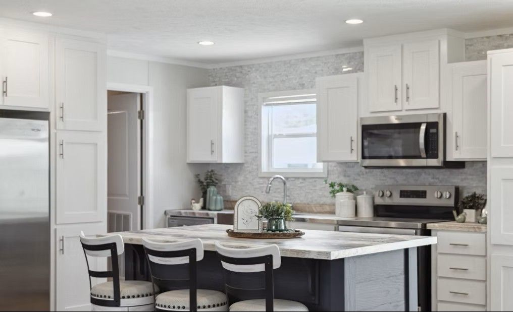 Modern kitchen with white cabinets, stainless steel appliances, and a gray island with seating.