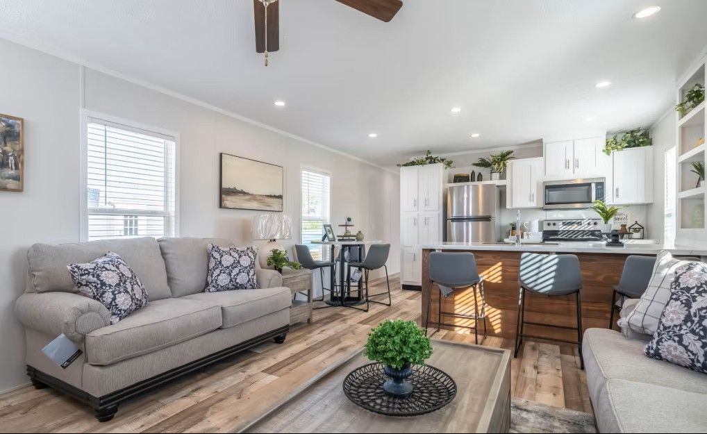 Bright, modern living space with couch, kitchen island, table, and white cabinetry.