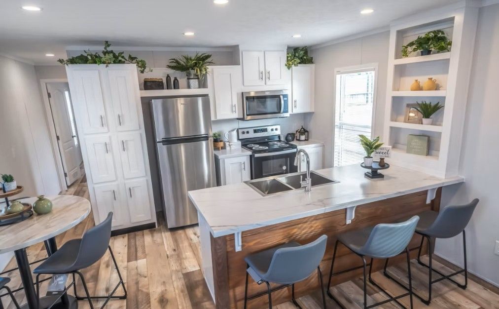 Bright kitchen with white cabinets, stainless steel appliances, and a wooden island with bar stools.