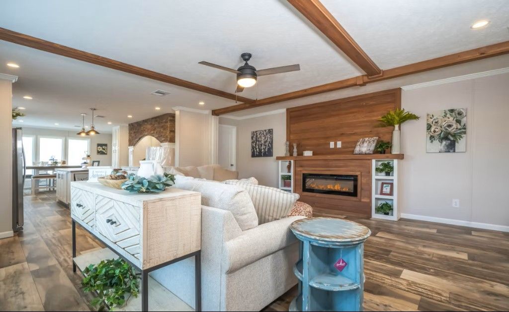 Living room with light-colored sofa, fireplace, wood accents, and ceiling fan.