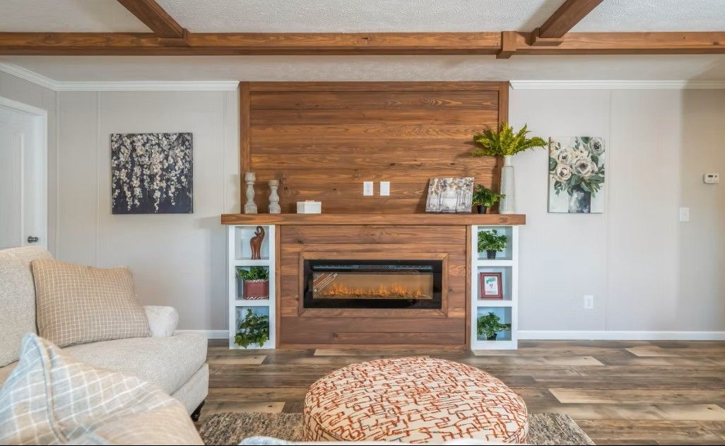 Living room with wood-paneled fireplace, built-in shelving, couch, and ottoman; neutral color scheme.