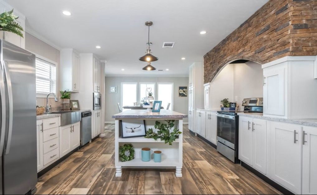 Modern kitchen with white cabinets, stainless steel appliances, and a wood-look floor. Island with open shelving.