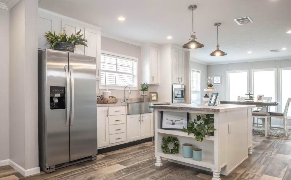 White kitchen with stainless steel fridge, island, and dining area.