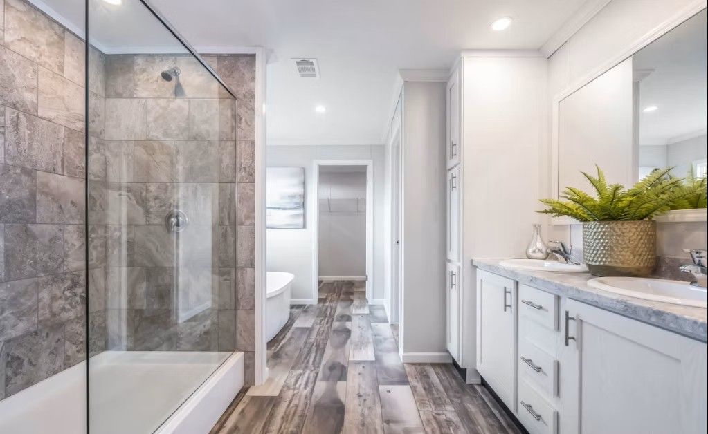 Bathroom interior with a glass shower, double vanity, and wood-look flooring.