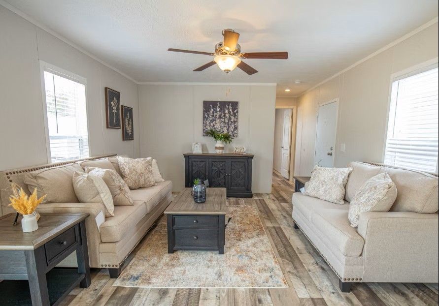 Living room with two sofas, a coffee table, and a decorative cabinet; light beige walls and wood-look flooring.