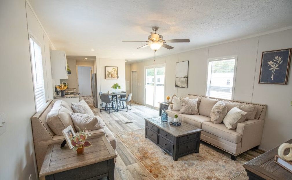 Spacious living room with tan sofas, coffee table, rug, dining area, and sliding glass door.