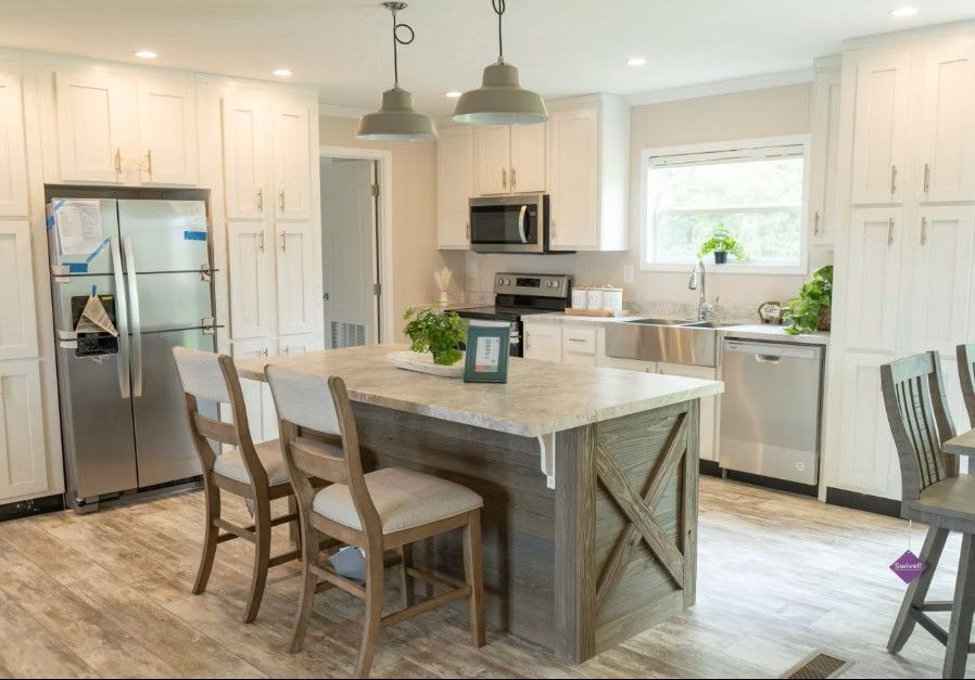 Bright kitchen with white cabinets, stainless steel appliances, and a gray island with seating.