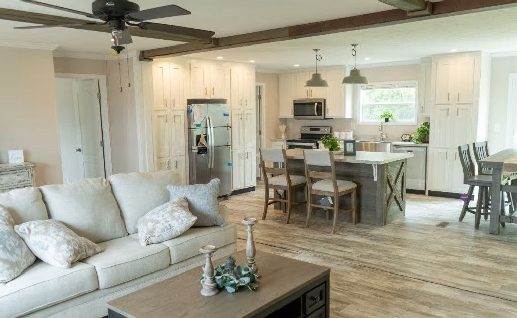 Open-concept living space with a kitchen and living room.  Beige couch, wooden island, and white cabinets.