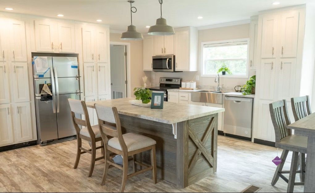 Kitchen with light wood floors, white cabinets, stainless steel appliances, and a rustic island with bar stools.