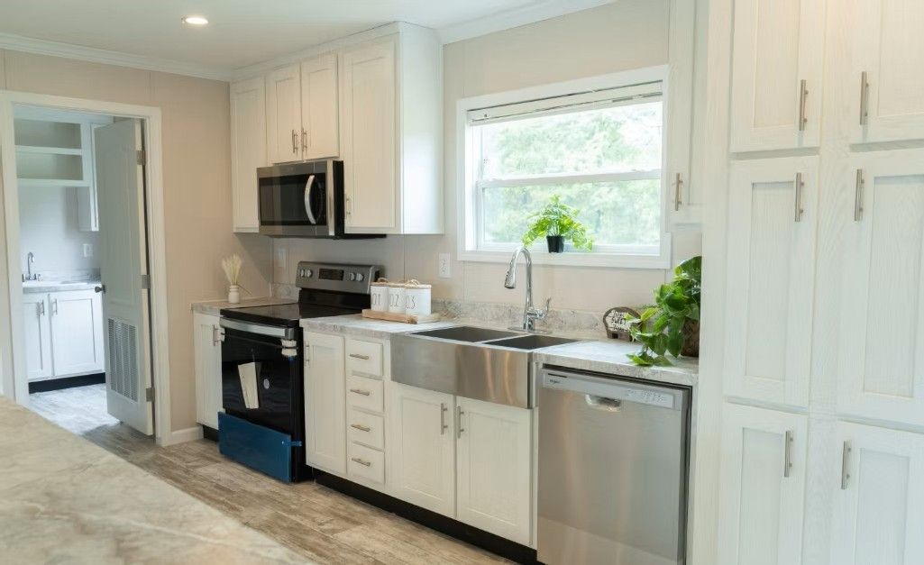 White kitchen with stainless steel appliances, cabinets, and a farmhouse sink.