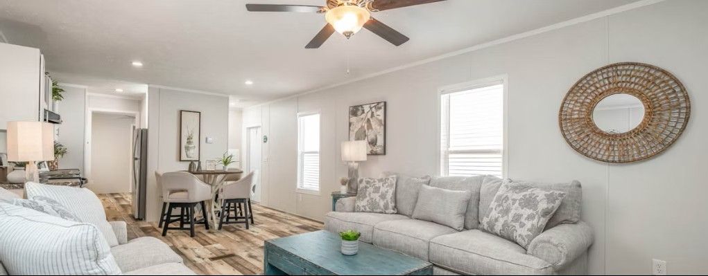 Living room with gray sofa, teal coffee table, and large round mirror.