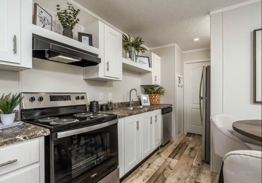 Modern kitchen with white cabinets, stainless steel appliances, and wood-look flooring.