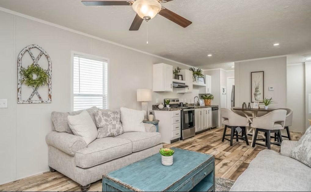 Living room and kitchen with light walls, wood-look floors, and teal coffee table.