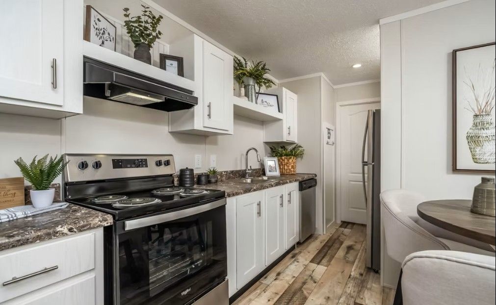 Kitchen with white cabinets, stainless steel appliances, and wood-look flooring.