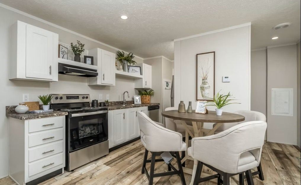 Kitchen with white cabinets, stainless steel appliances, and a small dining table with four chairs.