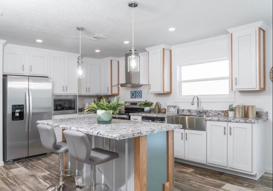Modern white kitchen with stainless steel appliances, granite countertops, and an island with bar stools.