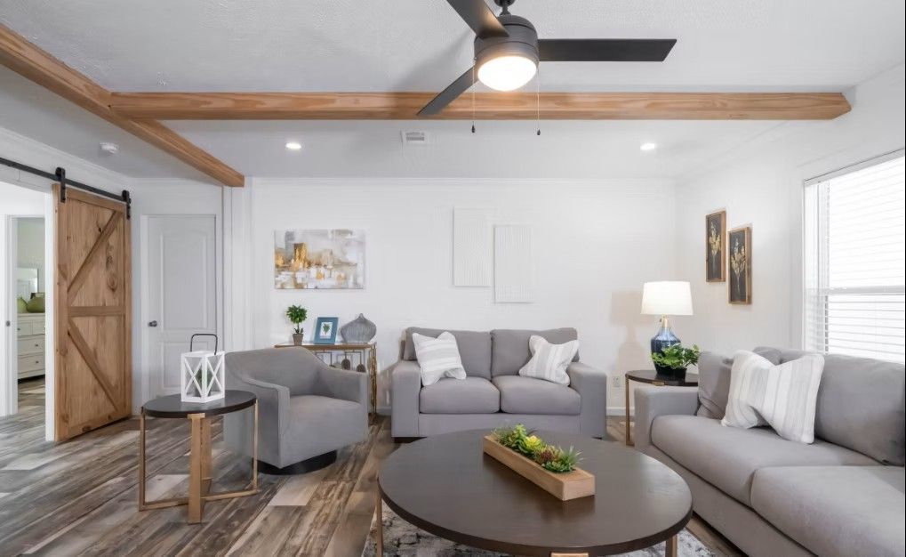 Living room with grey furniture, wooden beams and a barn door.