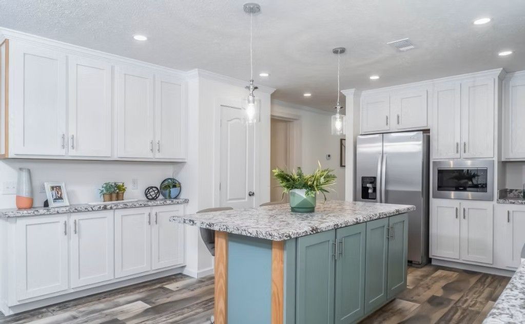 Modern kitchen with white cabinets, blue island, granite countertops, and stainless steel appliances.