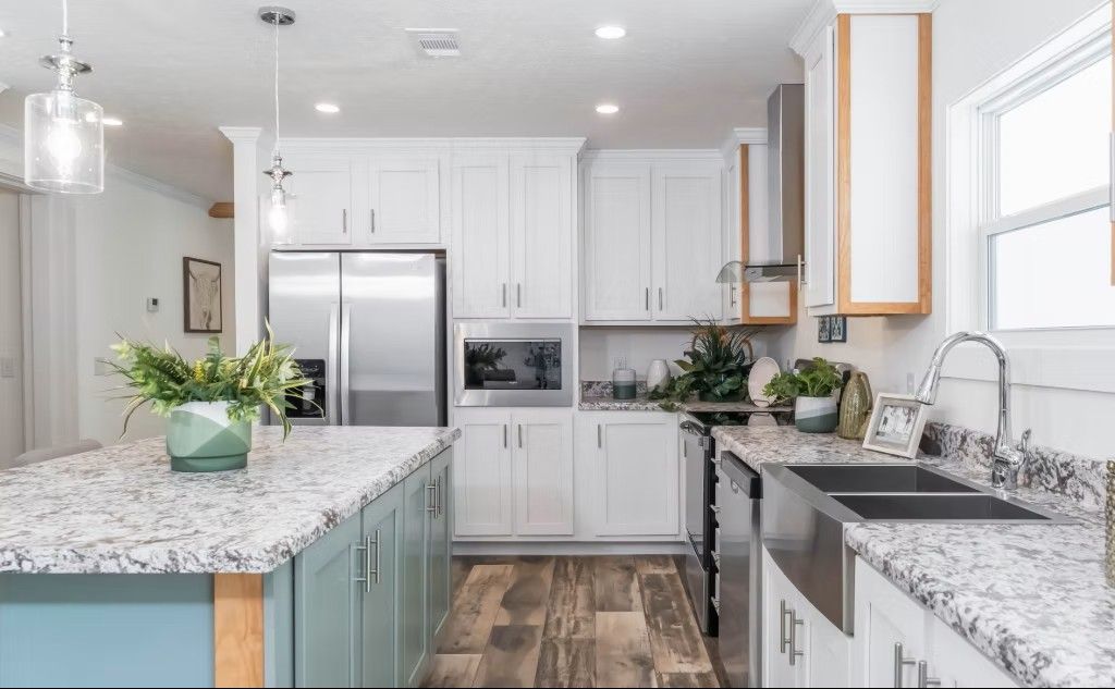 Modern kitchen with white cabinets, stainless steel appliances, and a blue island with a granite countertop.