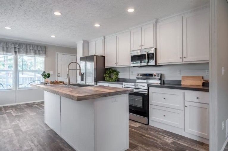 White kitchen with island, stainless steel appliances, and wood-look flooring.