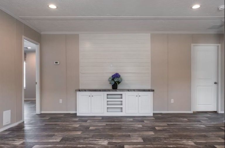 Living room with white cabinets, wood-look floor, and shiplap wall.
