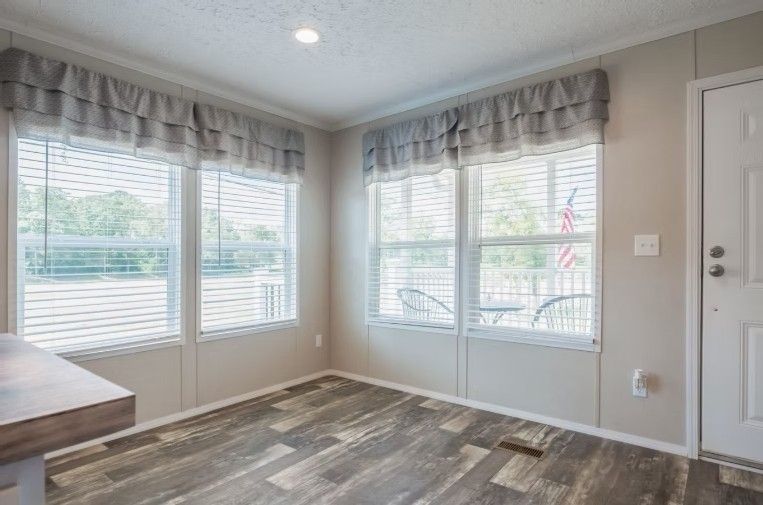 Interior room with large windows, light gray walls, and wood-look flooring.