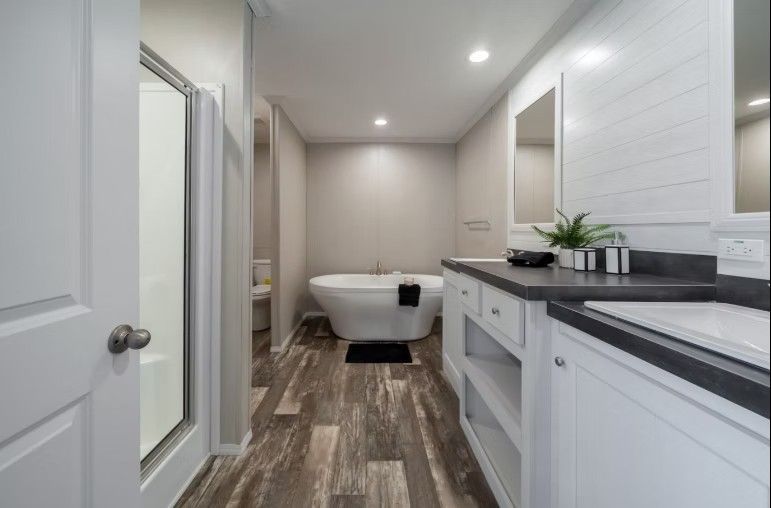 Bathroom with white cabinets, freestanding tub, shower, wood-look floor, and a countertop.