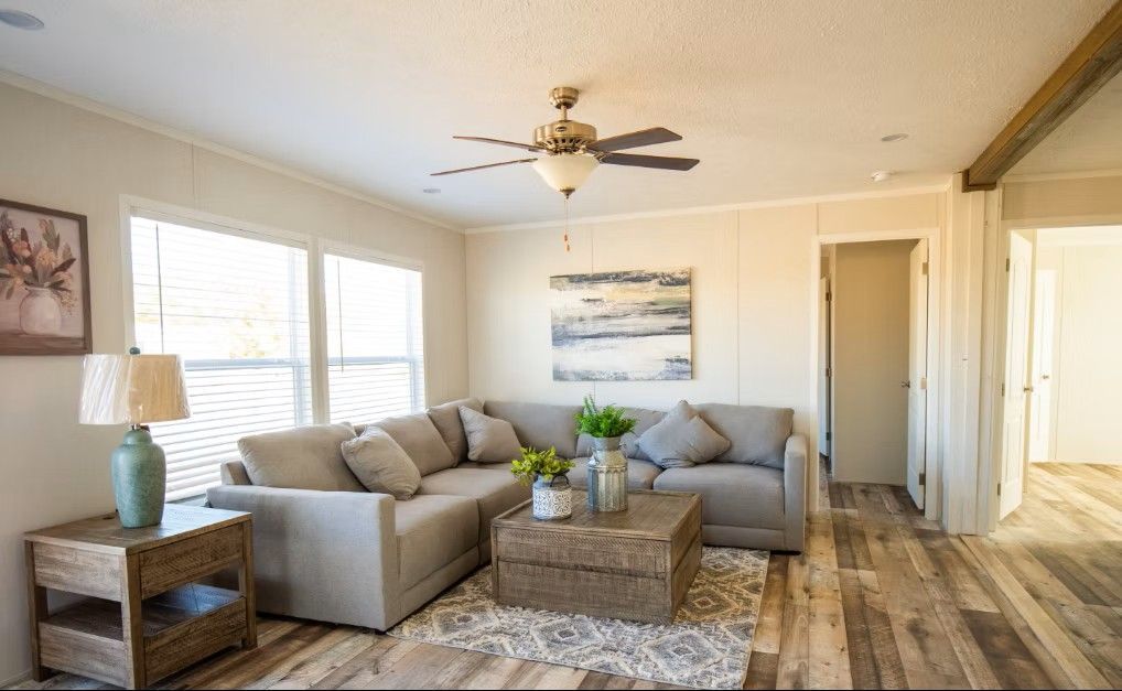 Living room with sectional sofa, coffee table, and artwork. Natural light and wood floors.
