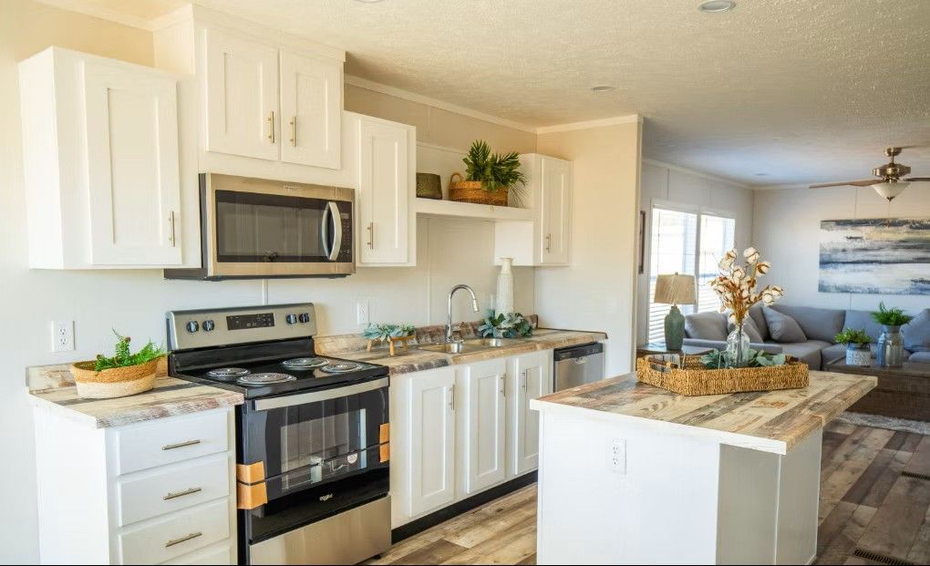 White kitchen with stainless steel appliances, countertop island, and open view into living room.