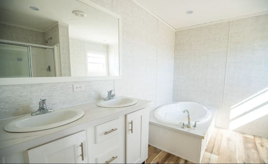 White bathroom with double sink vanity, oval tub, and a large mirror.