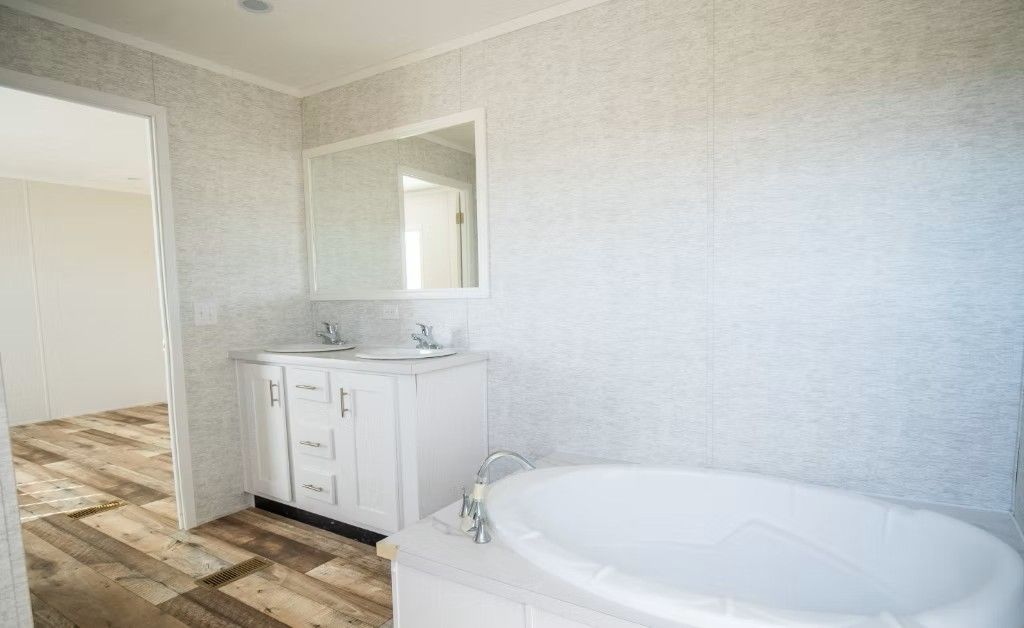 Bathroom with white vanity, tub, and walls; wood-look floor.