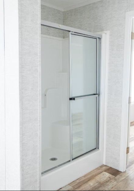 White shower stall with sliding glass doors, in a modern bathroom.