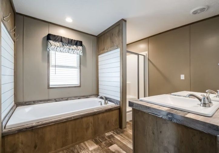 Bathroom with a bathtub, shower, and vanity. Brown and white tones with a window.