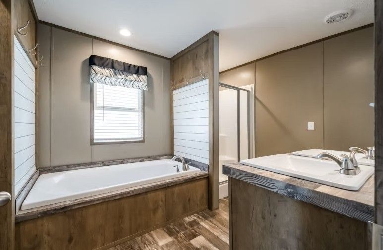 Bathroom with bathtub, shower, and double vanity; brown and beige tones, natural light.