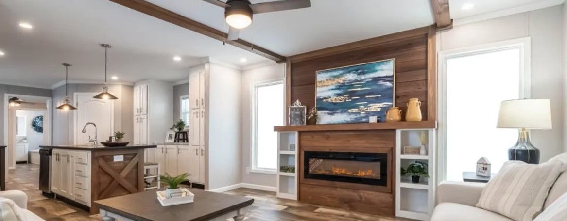 Living room with fireplace, kitchen island, and ceiling fan. Wooden accents, neutral tones, and modern design.