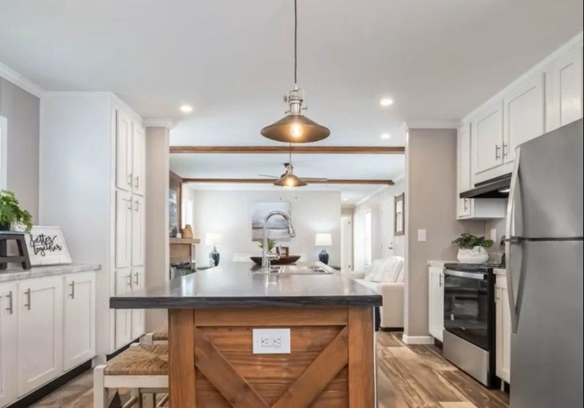 Kitchen with white cabinets, wooden island, open to living room with neutral colors.