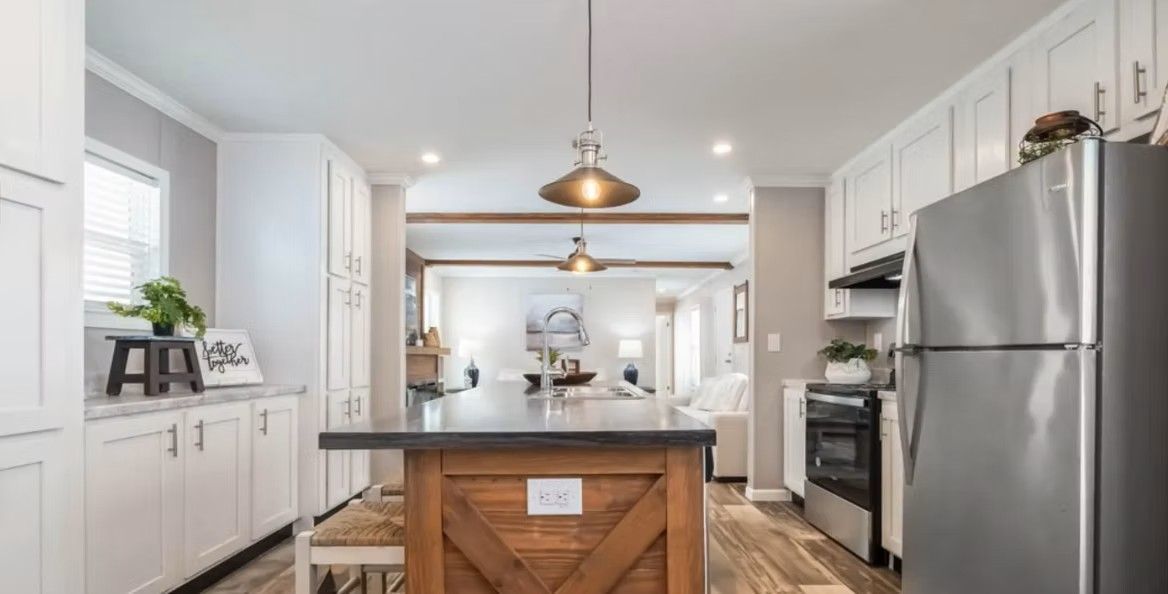 Kitchen with white cabinets, wood island, and stainless steel appliances; view into living room.