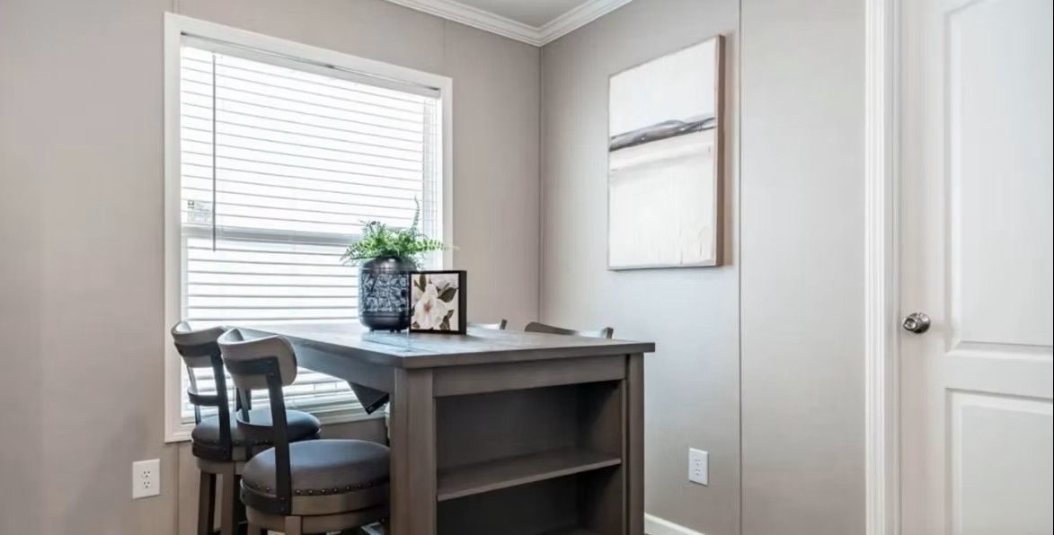 Small dining area with a table, chairs, window with blinds, artwork, and a door.