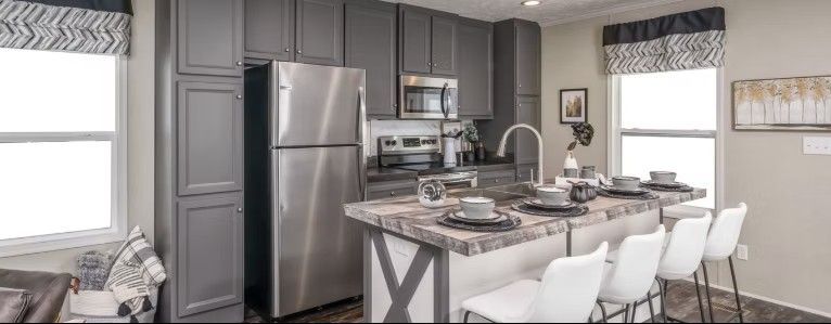 Modern kitchen with gray cabinets, stainless steel appliances, and a breakfast bar.