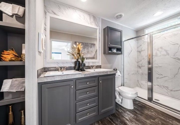 Bathroom with grey vanity, large mirror, and glass shower with marble-look wall.