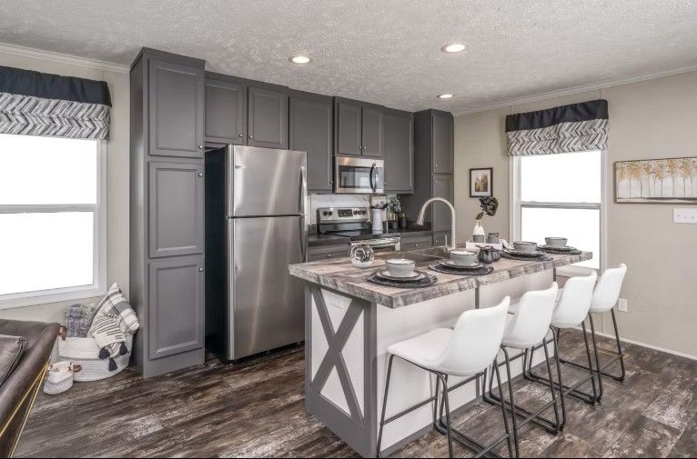 Gray kitchen with stainless steel appliances, island with seating, and wood-look flooring.