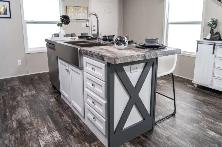 Kitchen island with a sink, drawers, and an X-shaped accent, with a countertop and stool.