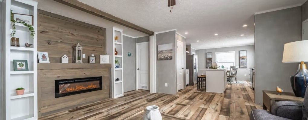 Living room interior with a fireplace, shelves, and hardwood floors.