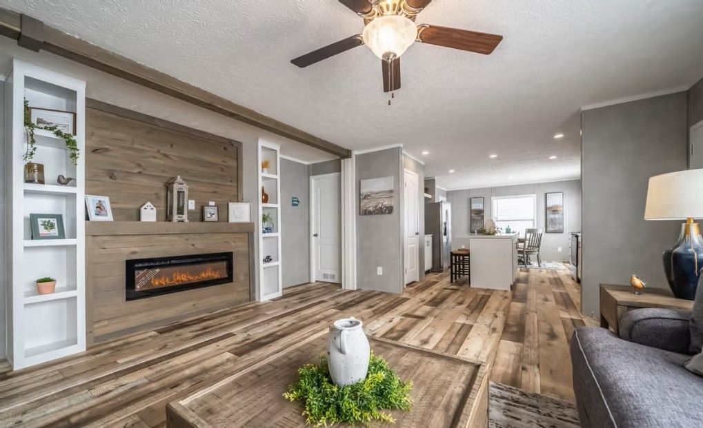 Living room with fireplace, shelving, wood flooring, and view into the kitchen.