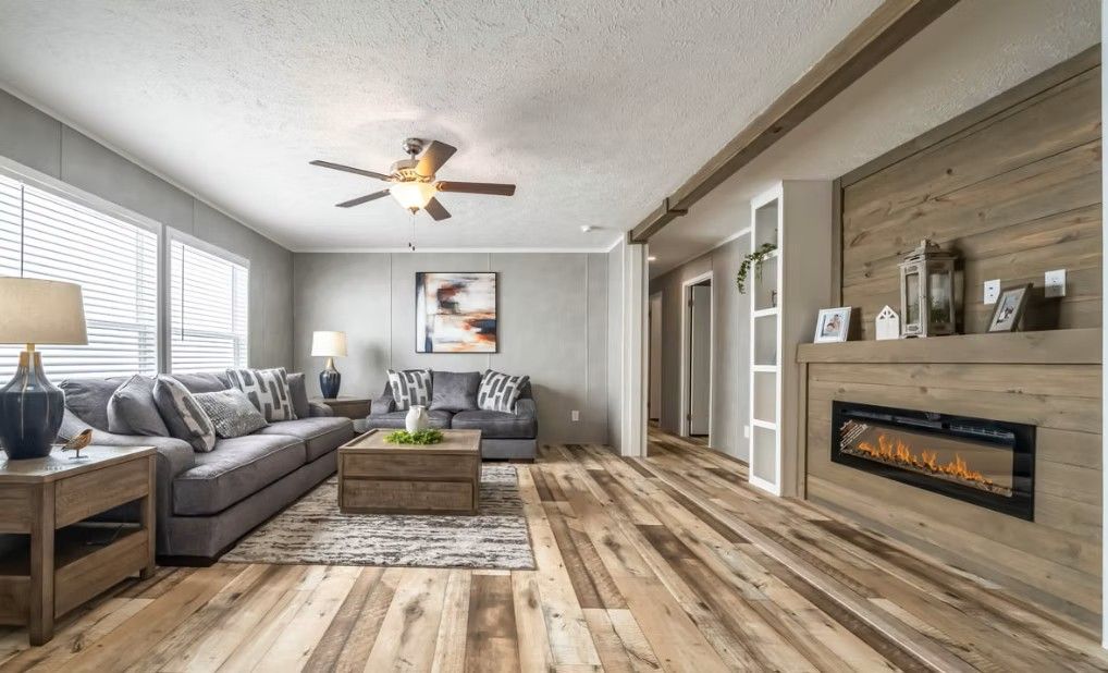 Living room with gray sofa, fireplace, wood floor, and natural light.