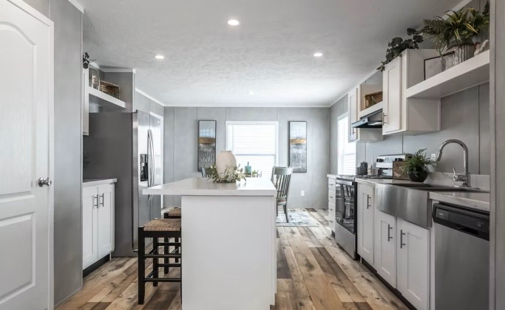 Modern kitchen with white cabinets, island, and stainless steel appliances.